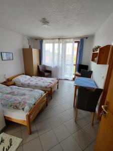 a room with two beds and a desk and a window at Pension Nela in Klatovy