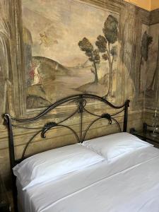 Ce lit se trouve dans une chambre ornée d'une peinture murale. dans l'établissement Villetta la Colombaia, à Carzano