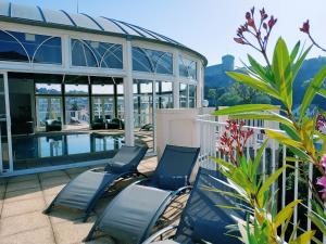 een patio met 2 stoelen en een zwembad bij Hôtel La Solitude in Lourdes