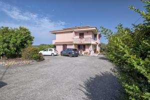 una casa rosa con dos coches aparcados en una entrada en Il Risveglio, en Codrongianos