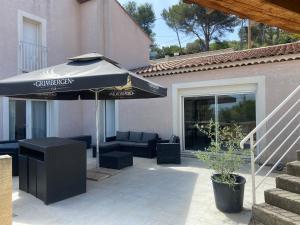 eine Terrasse mit einem Sonnenschirm, einem Sofa und Stühlen in der Unterkunft Petite maison avec accès jacuzzi in Istres