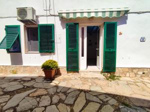 a white house with green shutters and a door at Casina Tecla in Cavo