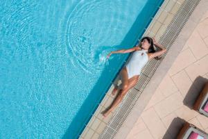 a woman in a white dress standing in a swimming pool at St Raphael Resort in Limassol