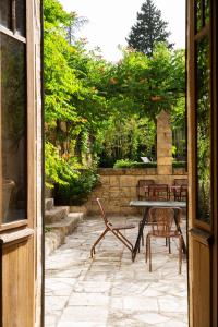 a patio with a table and chairs and trees at Prieuré Saint-Nicolas - Les Maisons in Blauzac
