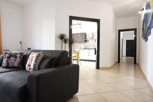 sala de estar con sofá negro y cocina en Casa vacanza Luna, en Cassibile