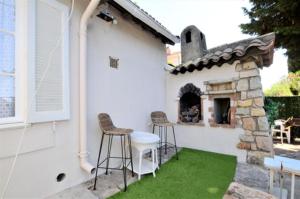 une terrasse avec deux tabourets et une cheminée en pierre dans l'établissement Maison provençale vue mer, à Vallauris