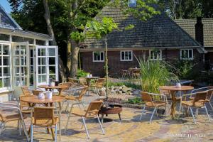 a patio with tables and chairs in front of a building at OP ZESTIEN in Hippolytushoef