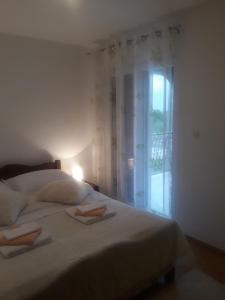 um quarto com uma cama branca e uma janela em Apartman Lana em Kijevo