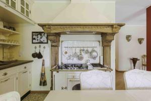 a kitchen with a stove and some white chairs at Villa Marzia in Lanzo dʼIntelvi