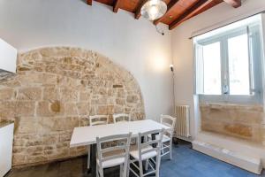 a dining room with a white table and a stone wall at Aquatica Home in Polignano a Mare