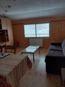 ein Wohnzimmer mit einem Sofa und einem Tisch in der Unterkunft Grand appartement au pied des pistes au cœur des Rousses in Les Rousses