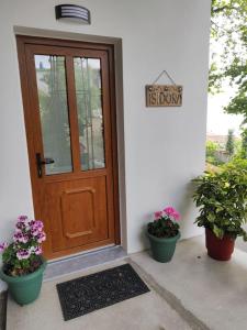 a door with two potted plants and a sign that reads first porch at Isidora Apartments in Zagora