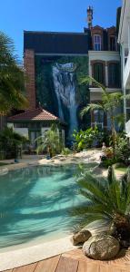 uma piscina em frente a um edifício com uma cascata em Appt Ambiance Chalet 2ch Piscine lagon em Tarbes