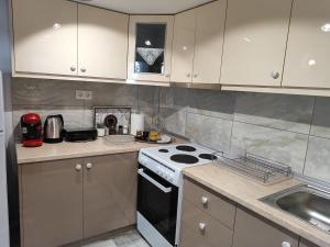 a kitchen with white cabinets and a stove and a sink at Isidora Apartments in Zagora