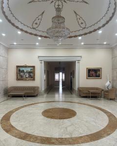 a large room with a chandelier and a large rug at Акку in Astana