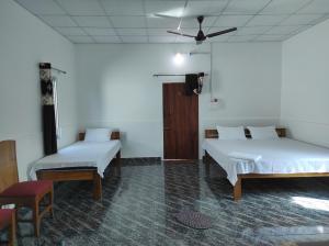 a room with two beds and a ceiling fan at Falcon Jungle Resort in Jyoti Gaon