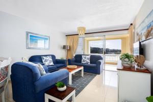a living room with two blue chairs and a television at Laguna La Crete 26 in Uvongo Beach