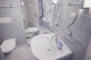 bagno con lavandino, servizi igienici e specchio di Lake Guest Haus a Därligen