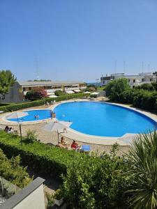 una gran piscina con personas sentadas bajo una sombrilla en Pausa Mare Seaside, en Torre a Mare