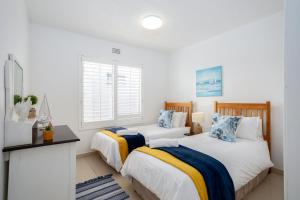 two beds in a room with white walls at Laguna La Crete 26 in Uvongo Beach +24 photos