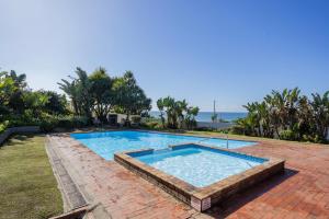 a large swimming pool with a brick walkway around it at Laguna La Crete 26 in Uvongo Beach