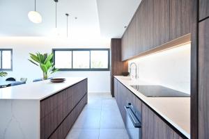 a kitchen with wooden cabinets and white countertops at Modern 3BR retreat in the Old North by HolyGuest in Tel Aviv