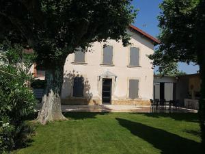 uma grande casa branca com uma árvore no quintal em Villa familiale au coeur d'un village provençal em Sarrians