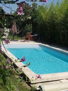 een blauw zwembad met een tafel en wat bloemen bij Villa familiale au coeur d'un village provençal in Sarrians