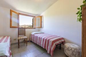 een slaapkamer met een bed, een stoel en een raam bij Casa Pisaro Lu Bagnu in Castelsardo