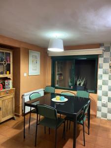 a dining room with a black table and green chairs at Finca Valdegrullas in Candeleda