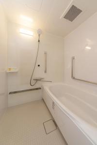 a white bathroom with a tub and a shower at Suikouen Hotel in Kurume