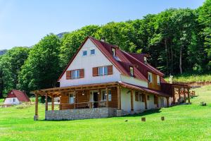 a large house with a red roof on a green field at Apartments CENTER OF THE WORLD in Žabljak