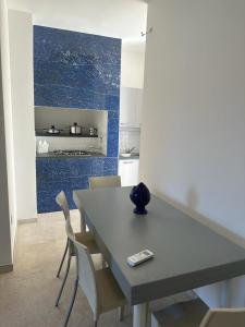 una mesa y sillas en una cocina con una pared azul en CASA APPRODO, en Porto Cesareo