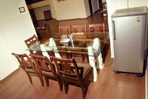 a glass dining room table with chairs and a refrigerator at Garava Villa Lonavala in Khandala