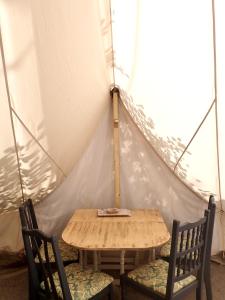 einen Holztisch und zwei Stühle in einem Zelt in der Unterkunft The Toad's pad in Tiverton