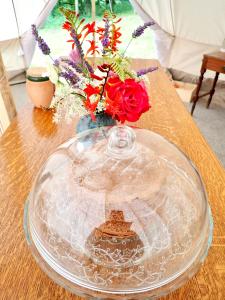 un piatto di vetro con un vaso con fiori su un tavolo di The Toad's pad a Tiverton