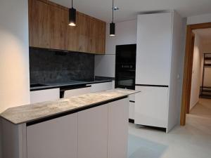 una cocina con armarios blancos y electrodomésticos negros en Apartamento en pleno centro en Alhama de Murcia