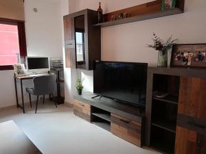 ein Wohnzimmer mit einem Flachbild-TV und einem Schreibtisch in der Unterkunft Apartamento 2 Dormitorios En el Centro in Alhama de Murcia