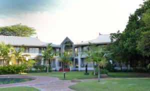 a large white building with a pool and trees at Cresta Lodge Harare in Harare