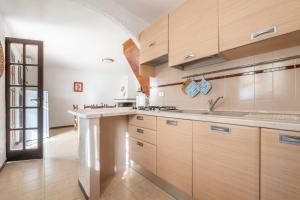 uma cozinha com armários de madeira e um lavatório em Spiaggia Grande Junior em Calasetta