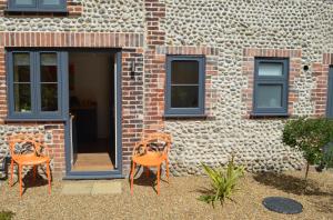 two orange chairs sitting in front of a brick building at Bloomsbury House - Magical Coastal Retreat - Crabpot Cottages in Sheringham