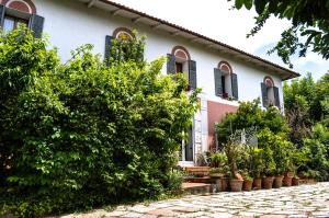 Baricella的住宿－Bed & Breakfast Il Giardino，白色的房子,有黑色百叶窗和灌木