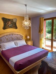 a bedroom with a purple bed with a chandelier at Villa Marzia in Lanzo dʼIntelvi