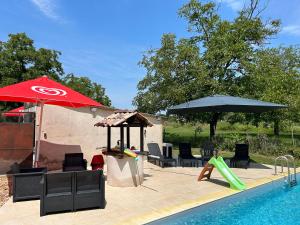 een zwembad met stoelen en parasols en een zwembad bij Jolie Villa indépendante climatisée 3 chambres tout confort 6 couchages, piscine chauffée 4 X 8 disponible de Juin à fin Septembre, grand terrain clos, boulodrome éclairé, ping-pong, wifi, proche commerces et commodités Animaux domestiques sur demande in Bretenoux