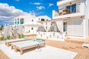 een wit huis met een patio met een tafel en een parasol bij Mar i Vent in Cala Blanca