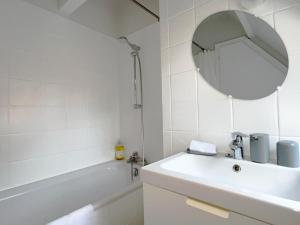La salle de bains est pourvue d'un lavabo, d'une baignoire et d'un miroir. dans l'établissement Le Balcon fleuri centre Robertsau tram Jardiniers, à Strasbourg