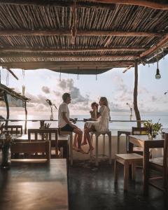 a couple sitting at a table in front of the ocean at Mr Kahawa Waterfront Suites in Paje