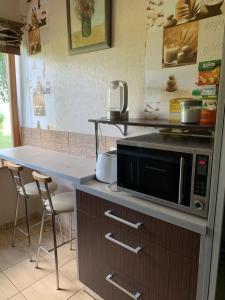 a kitchen with a microwave and a counter with chairs at Ģimenes māja “Rukši” in Dokupe