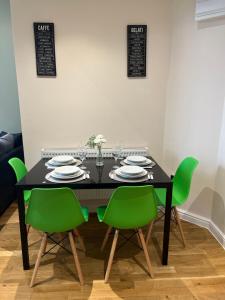 uma mesa preta com cadeiras verdes e pratos em Edgerton Suites em Huddersfield