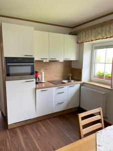 a small kitchen with white cabinets and a window at Plombergbauer in Sankt Gilgen